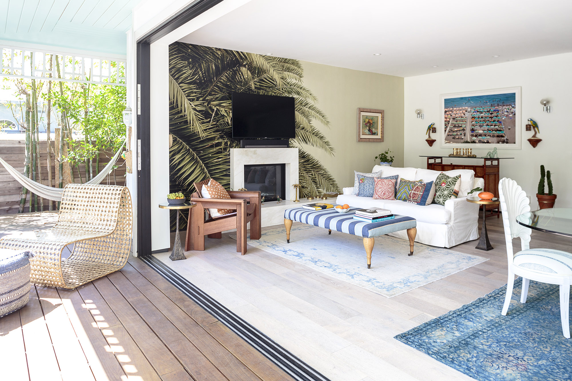 indoor outdoor transition with palm wallpaper accent wall rattan chair and hammock on deck